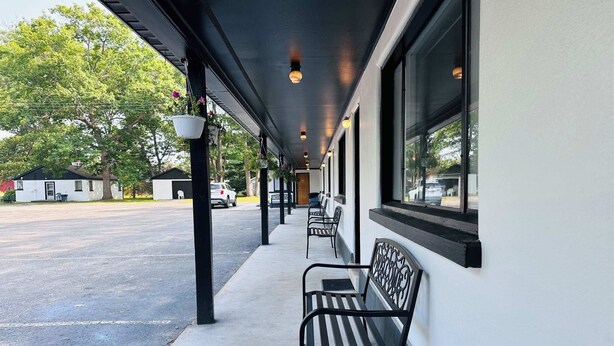 Un espace extérieur abrité, doté de bancs, d’un chemin et d’un bâtiment avec de grandes fenêtres.