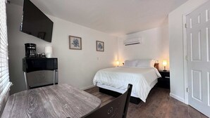 Quarto pequeno e limpo, com cama, mesas de cabeceira, escrivaninha com cadeira, TV de tela plana e ar condicionado.
