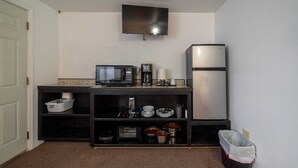 Una cucina compatta con forno a microonde, macchina del caffè e frigorifero.