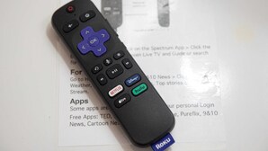 Une télécommande noire dotée d’un pavé directionnel bleu et de boutons portant les inscriptions « Netflix », « Hulu », « Roku » et « Apple TV+ ».