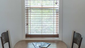A small table with a magazine in front of a window with blinds. - Room 1 at Inland Lakes Motel, Indian River, MI (Indian River)