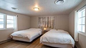 Een kamer met twee eenpersoonsbedden, een plafondventilator en een raam aan de linkerkant.