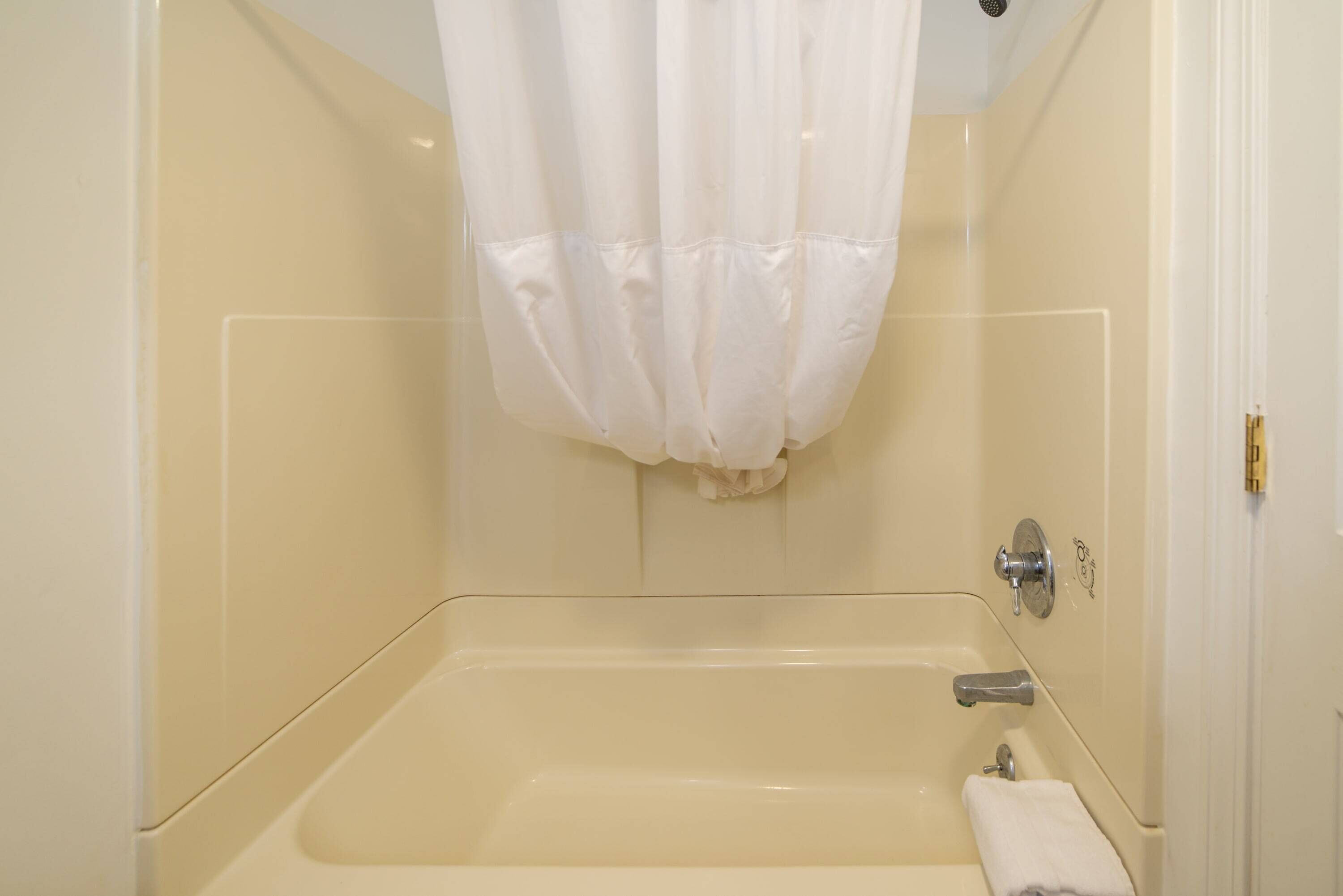 A bathroom with a bathtub, a shower curtain, and a towel rack.