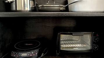 A kitchen shelf with a pot, a pan, and a white container. Below, a toaster oven is visible.