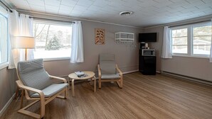 Ein Zimmer mit zwei Stühlen, einem kleinen Tisch, einer Lampe, einem Fernseher und einer Mikrowelle.