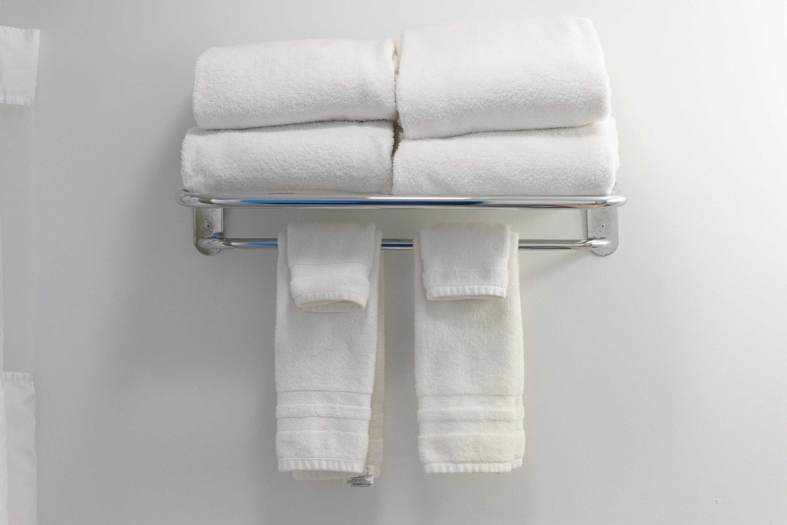 A bathroom with a towel rack holding folded towels and a pair of slippers.