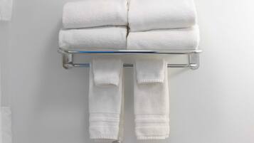 A bathroom with a towel rack holding folded towels and a pair of slippers.