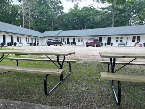 A building with multiple rooms, outdoor seating, and parked cars. - Room 5 at Inland Lake Motel, Indian River, MI (Indian River)