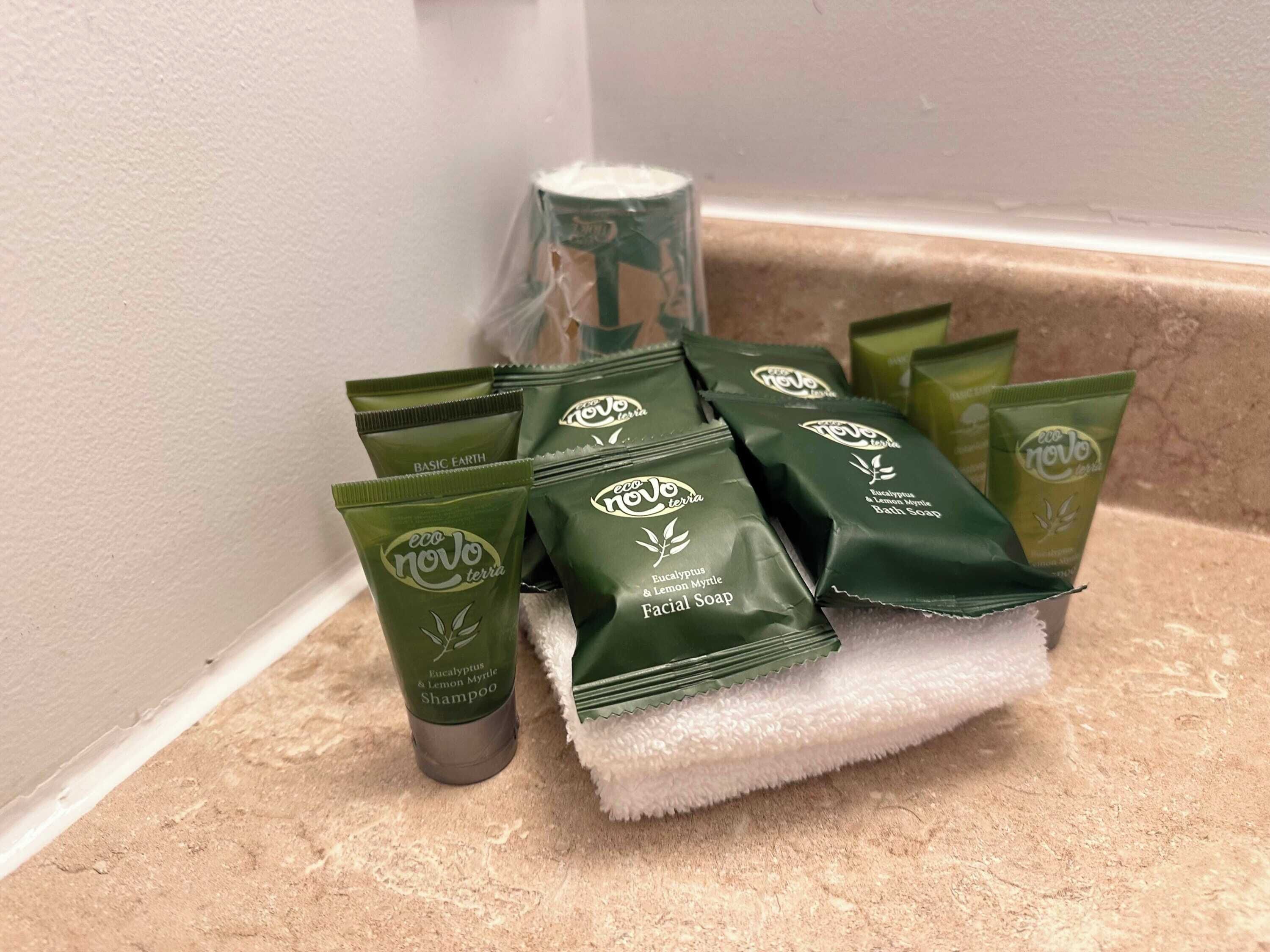 Ympäristöystävällisten henkilökohtaisten hygieniatuotteiden valikoima, johon kuuluu muun muassa kasvojenpesuaine ja shampoo, on asetettu kylpyhuoneen tasolle.