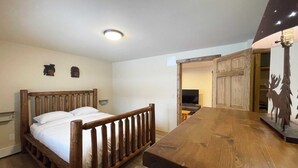 Un dormitorio con cama y mesa de madera, e iluminación en el techo.