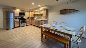 Una cocina moderna con armarios de madera, electrodomésticos de acero inoxidable y un comedor con mesa y sillas de madera.