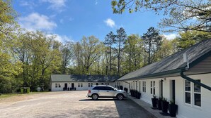 A building with a gravel driveway and a parked car. - Room 8 at Inland Lakes Motel, Indian River, MI (Indian River)