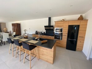 A modern kitchen with a central island, wooden cabinets, and stainless steel appliances.