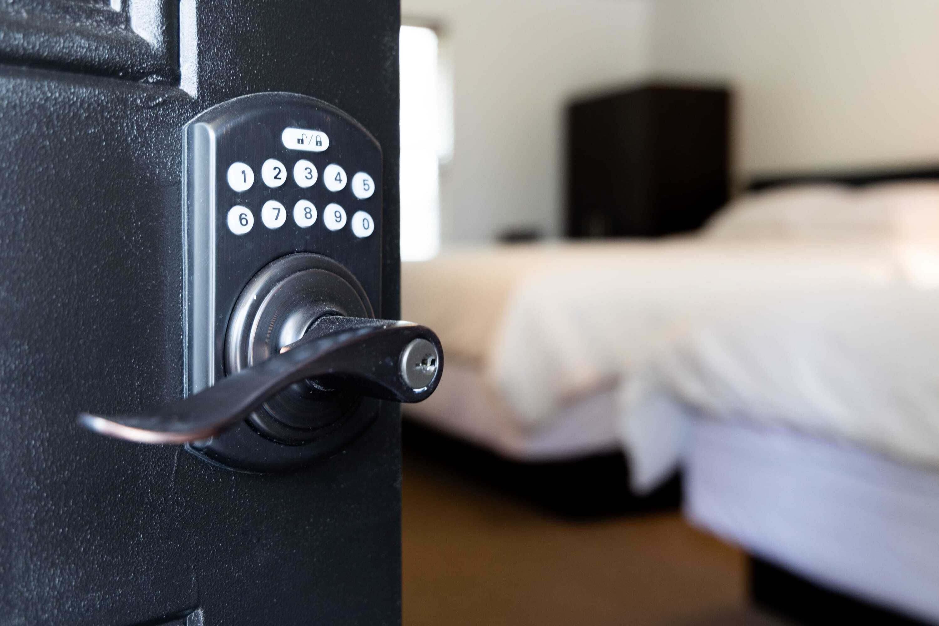 En dør til et hotelværelse med en kode lås og en nøglehul.