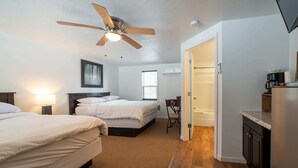 Une chambre avec deux lits, un ventilateur de plafond, une table de chevet et une fenêtre.