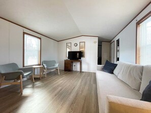 Un salon avec un canapé, deux fauteuils, un téléviseur et une petite table.