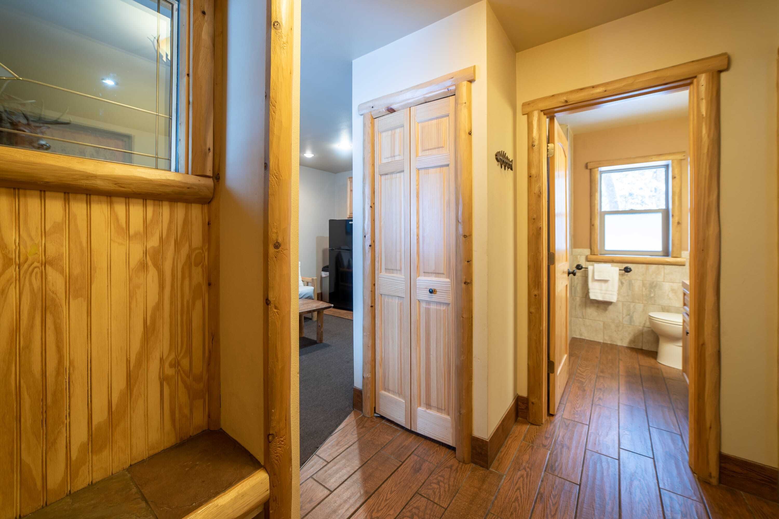 A wooden-floored hallway with a double door leading to a bathroom.