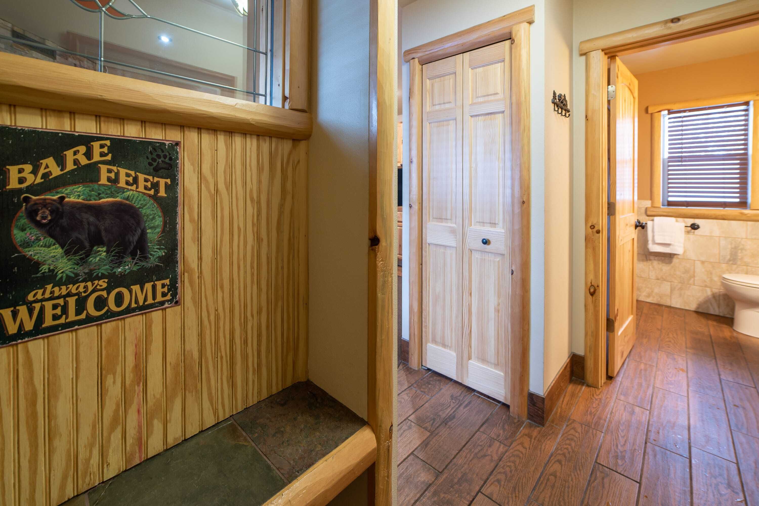 A wooden bench with a bear illustration and text, a wooden door, and a bathroom with a window and toilet.