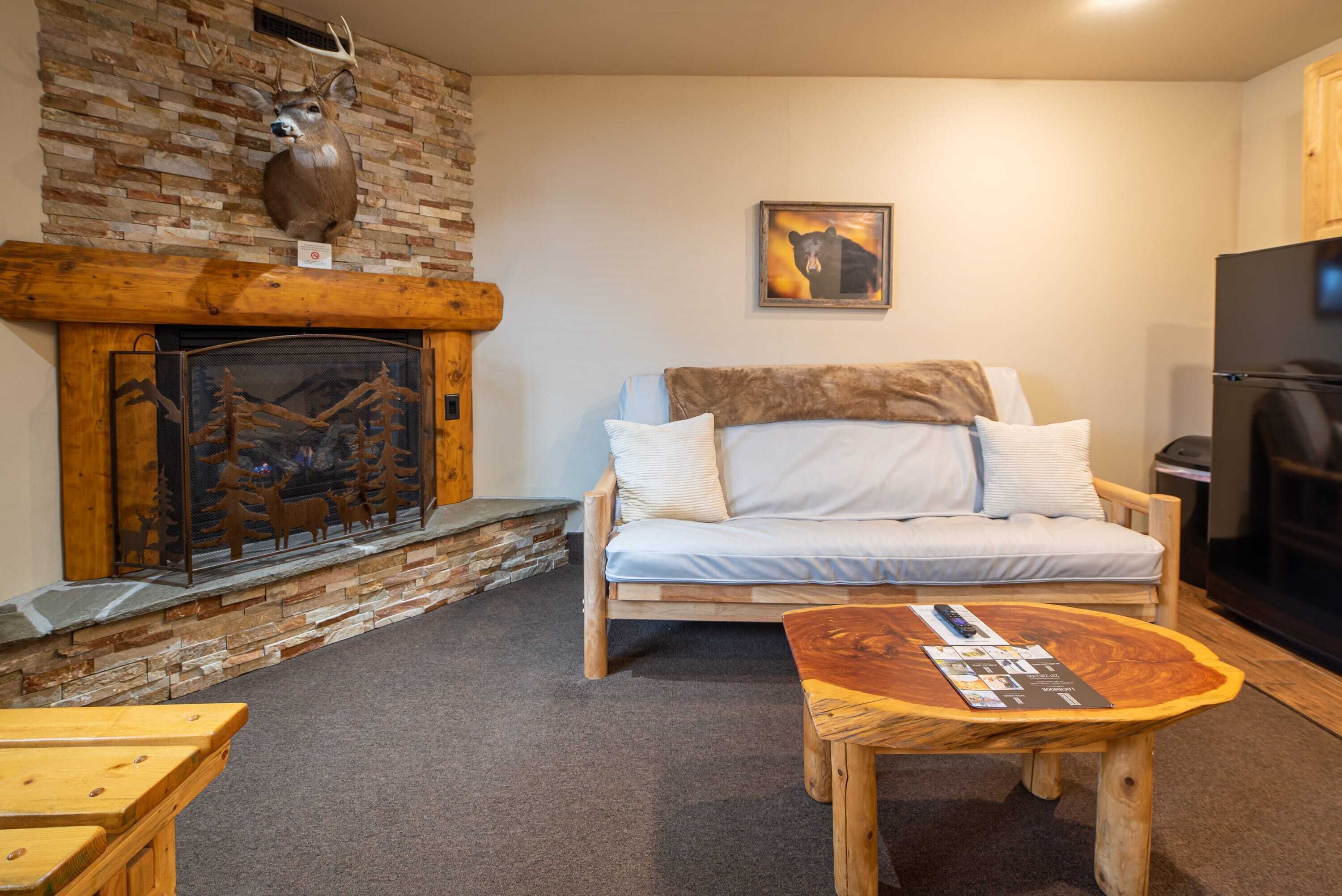 Ein gemütliches Wohnzimmer mit Kamin, einer Couch, einem Couchtisch und einem aufgehängten Hirschkopf.