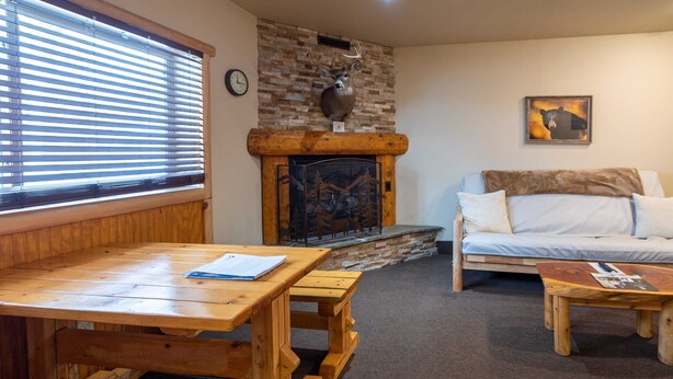 Ein gemütliches Wohnzimmer mit Kamin, Holzmöbeln und einer Couch.