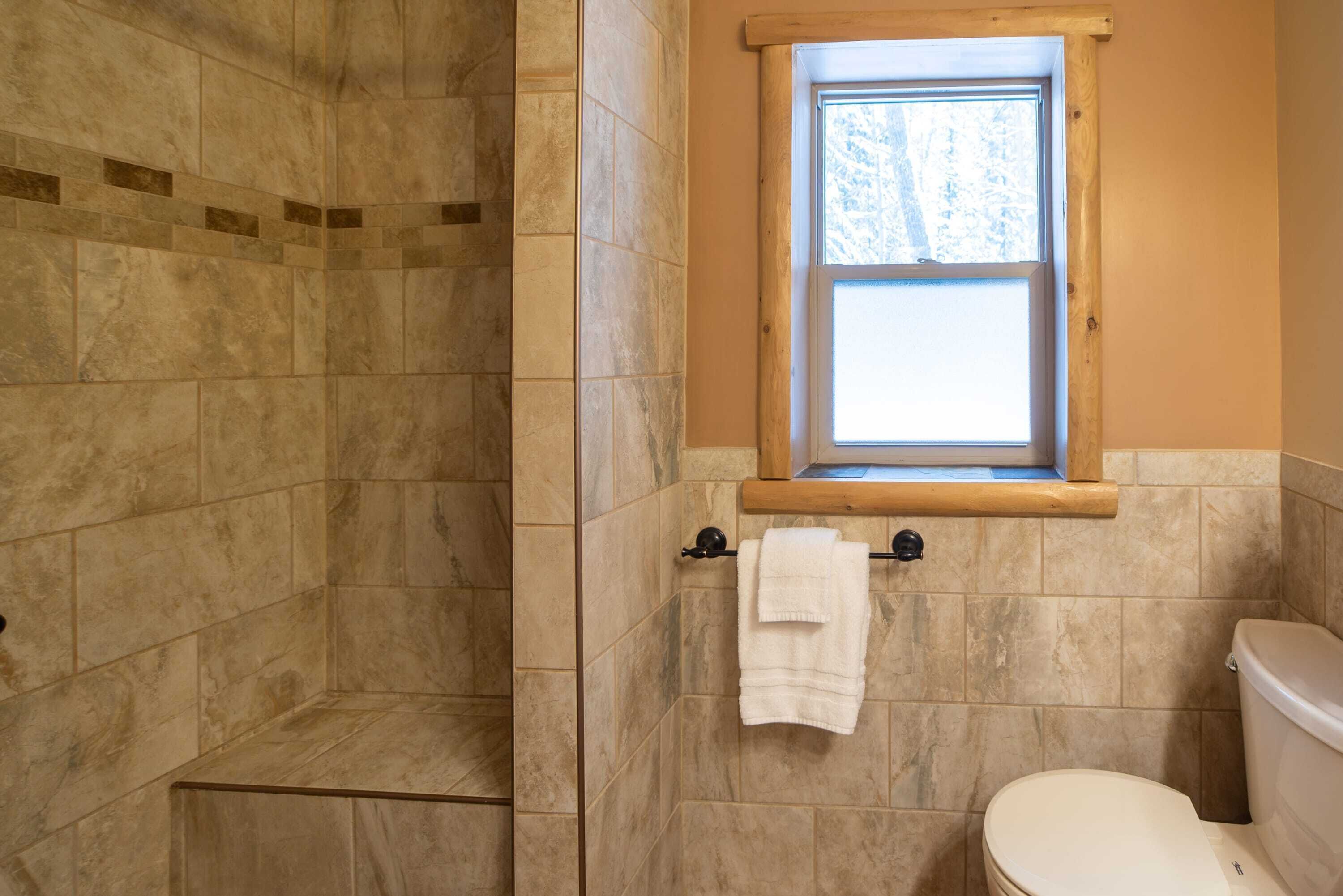 Une salle de bain avec une douche, des toilettes et une fenêtre.