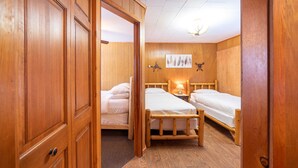 Une pièce en bois avec deux lits, une armoire en bois et un luminaire au plafond.