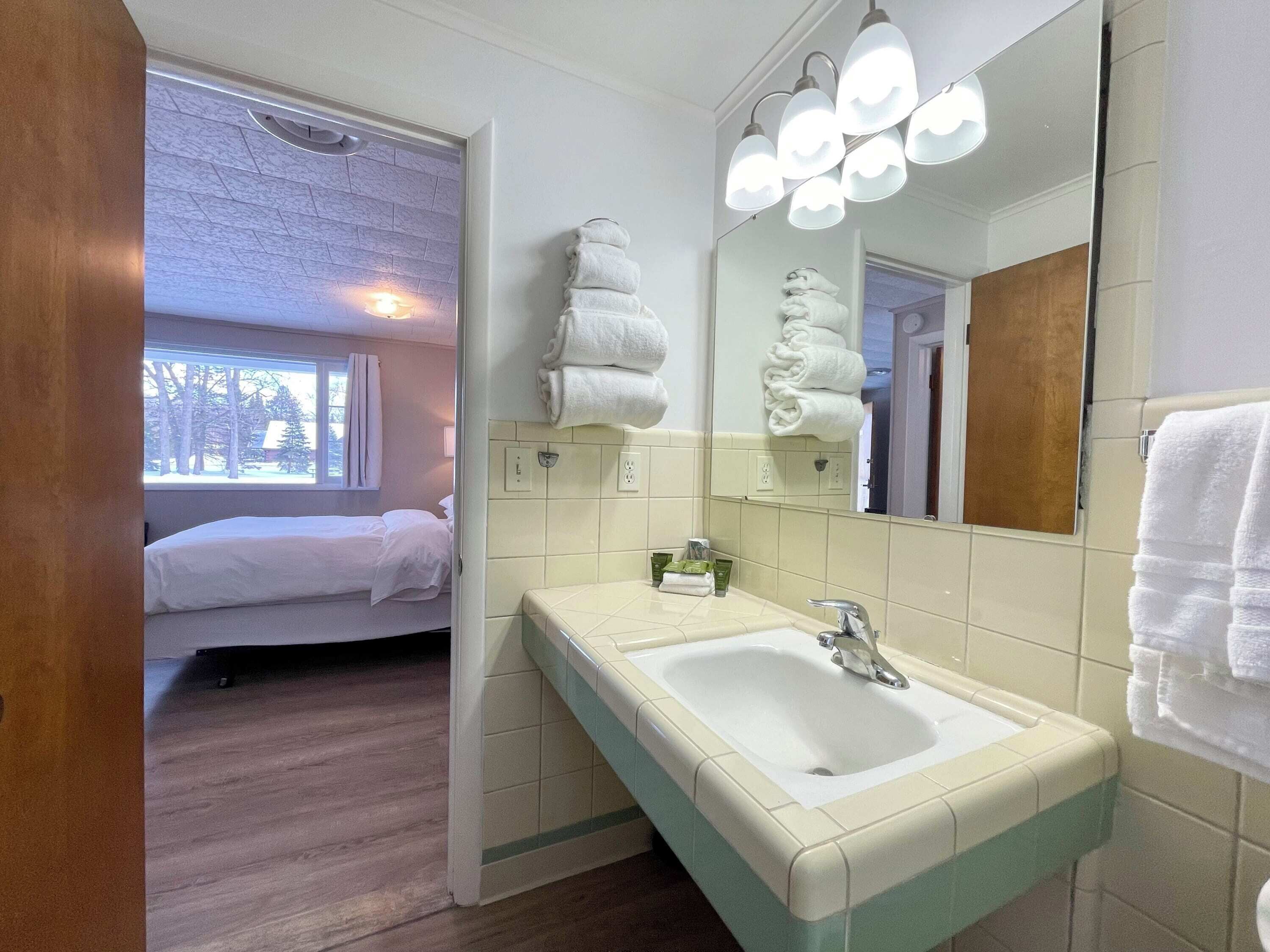 A hotel bathroom with a sink, mirror, and towels.