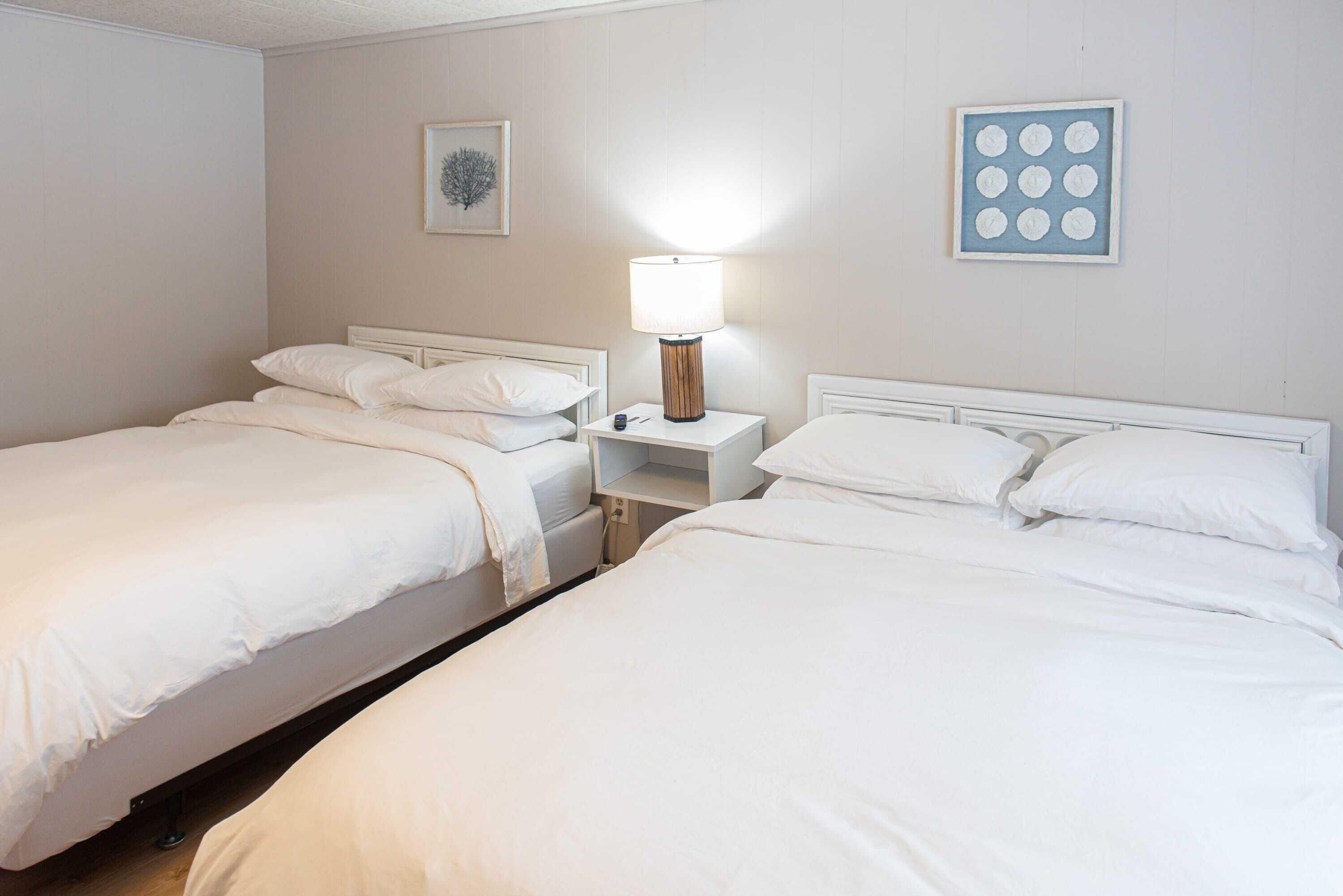 Una camera d'albergo con due letti singoli, un comodino con una lampada e un quadro appeso al muro.