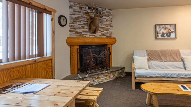 A cozy living room with a fireplace, wooden furniture, and a sofa. - The Wolverine Lodge at The Totem Lodges (Indian River)