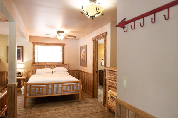 A wooden-framed bed with a headboard, a ceiling fan, and a window with blinds.