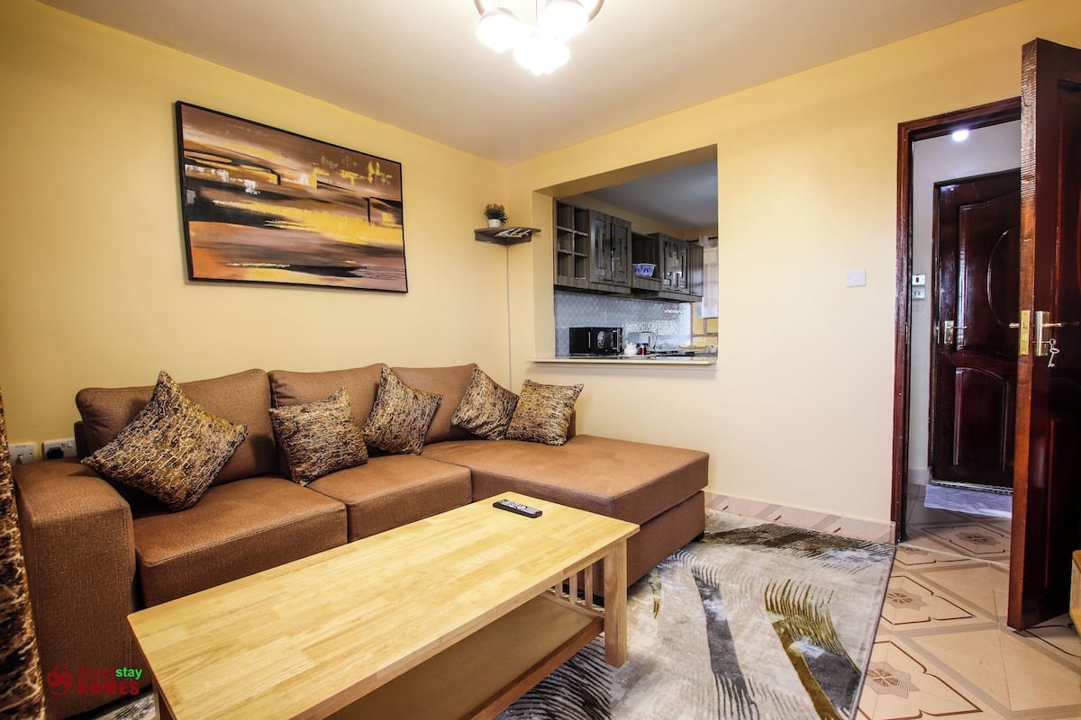 A living room with a brown sofa, a wooden coffee table, and a painting on the wall.