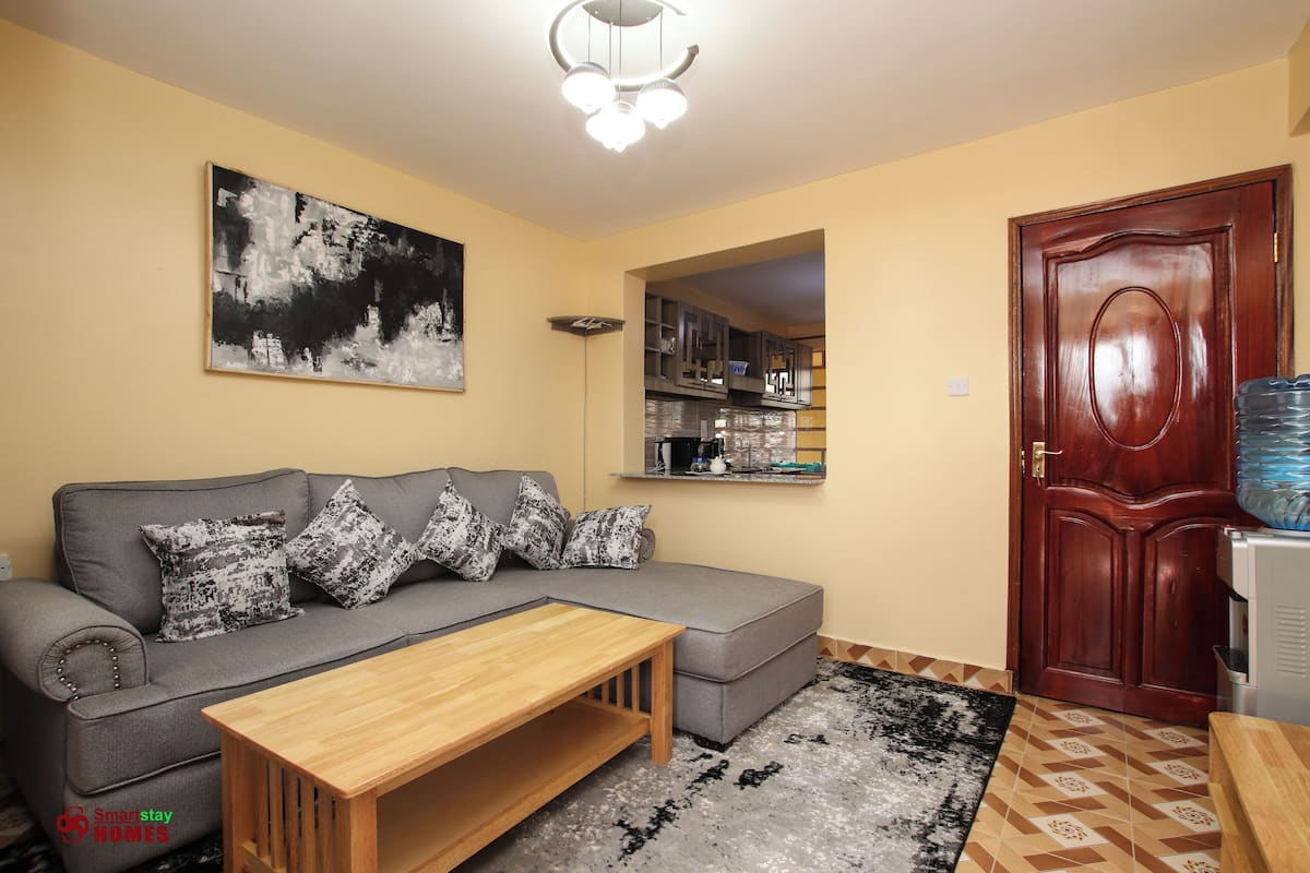 A living room with a grey sofa, wooden coffee table, and a black and white painting on the wall.