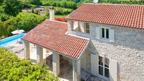 A stone house with a red-tiled roof, a swimming pool, and a view of green hills. - Villa Samanta - 6 Persons, 2 Bedrooms, Private Pool, Barbecue (Momjan)