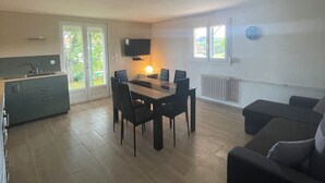 Ein geräumiger Wohnbereich mit Esstisch, einer Couch und einer Küchenzeile mit Fernseher.
