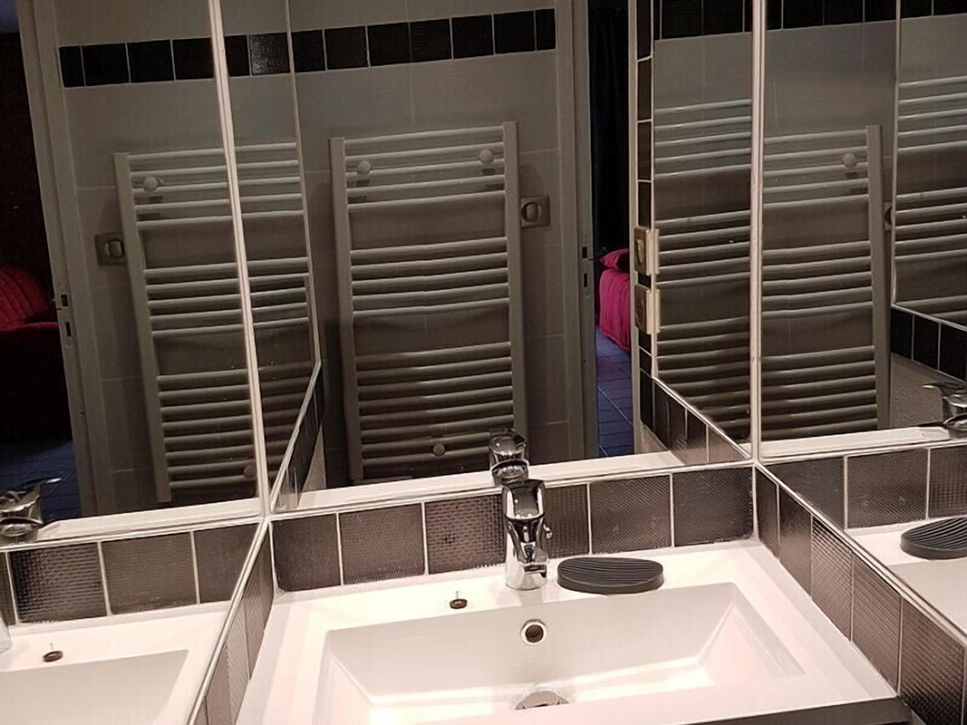 A bathroom with a large mirror, a sink, and a shower area with a glass door.
