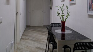 Ein schmales Entree mit Esstisch, Stühlen und einer Pflanzvase.