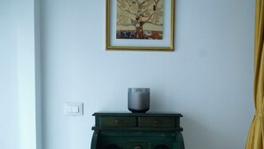 Ein Zimmer mit einem grünen Holzschrank, einem gerahmten Bild an der Wand und einem gelben Vorhang.