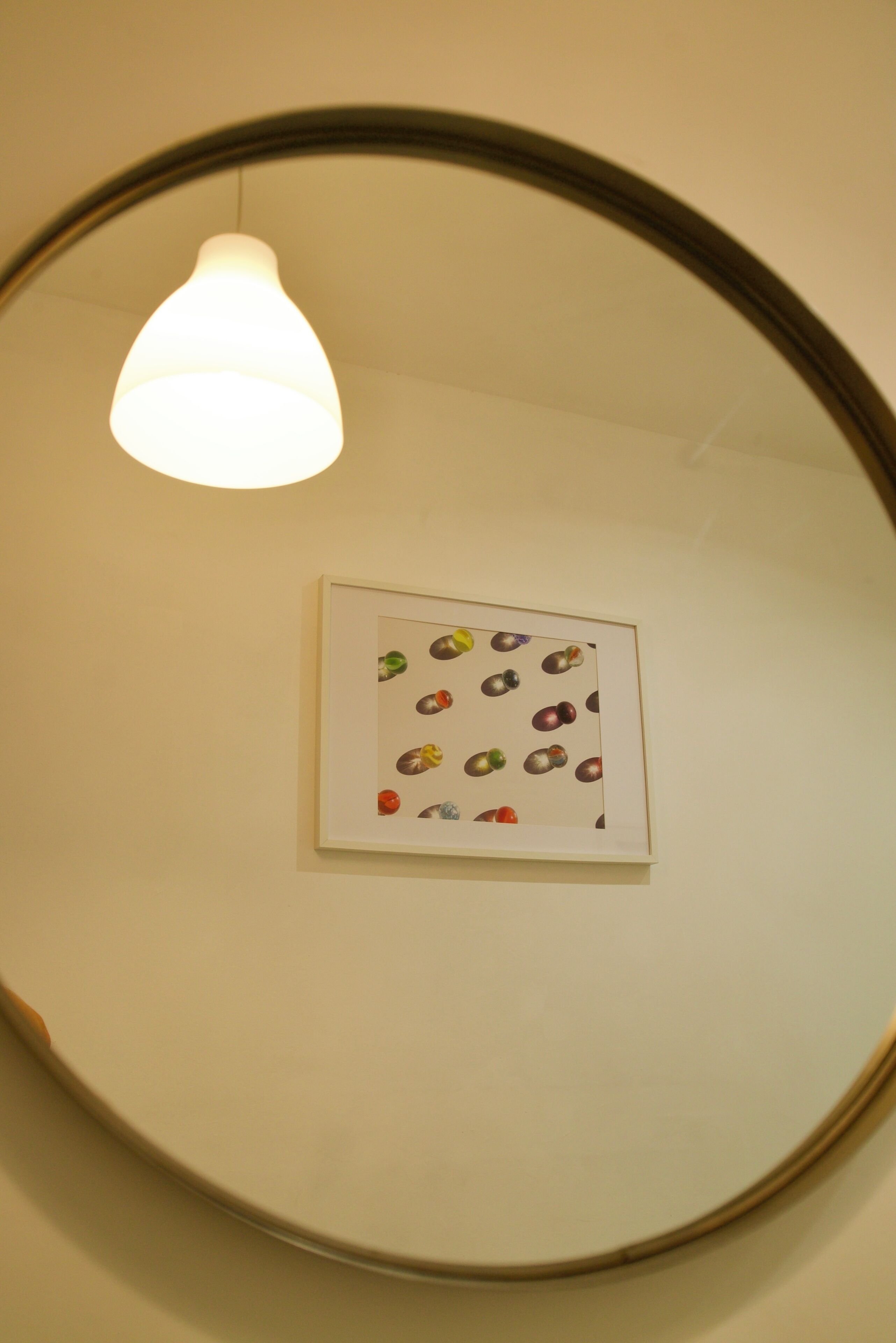 Una obra de arte enmarcada con un diseño de objetos de colores diversos en una pared.