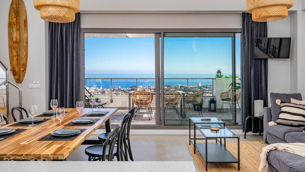 A modern living room with a dining area, large sliding glass doors leading to a balcony with a city view. - Top-floor Apartment With Pool Ref 20 (Benalmádena)