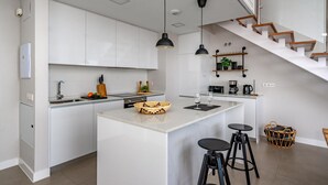 A modern kitchen with white cabinets, a central island with stools, pendant lighting, a staircase, and a coffee machine. - Top-floor Apartment With Pool Ref 20 (Benalmádena)