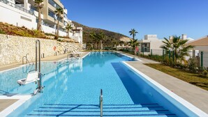 A swimming pool with clear blue water, surrounded by a stone wall and palm trees. - Top-floor Apartment With Pool Ref 20 (Benalmádena)