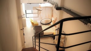 A staircase with a metal railing leading to a room with a bed, a chair, and a table. - Loft Imperial (Madrid)