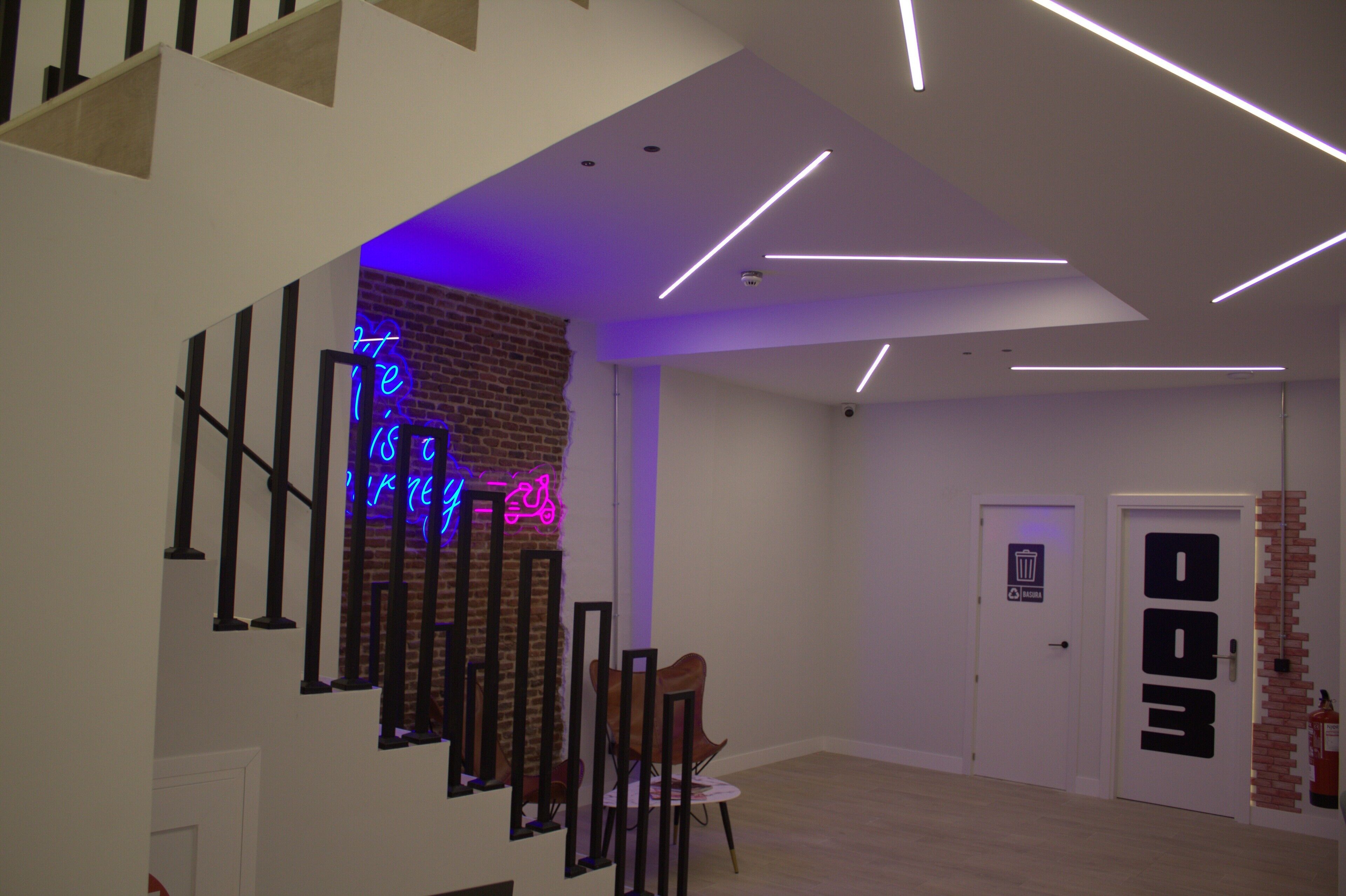 Een modern interieur met een trap, een neonbord en een brandblusser.