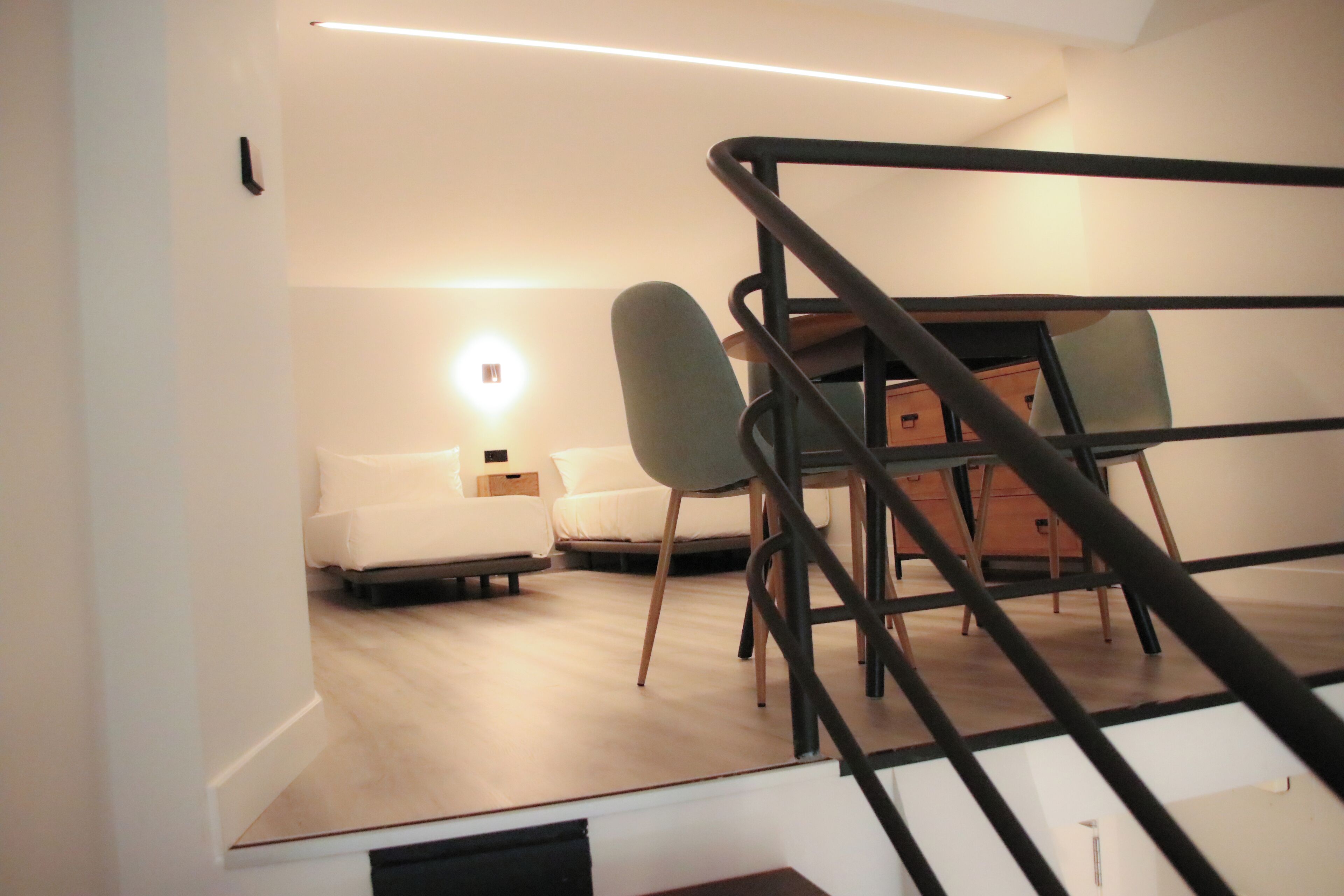 A modern, well-lit room with a bed, a desk, and a chair.
