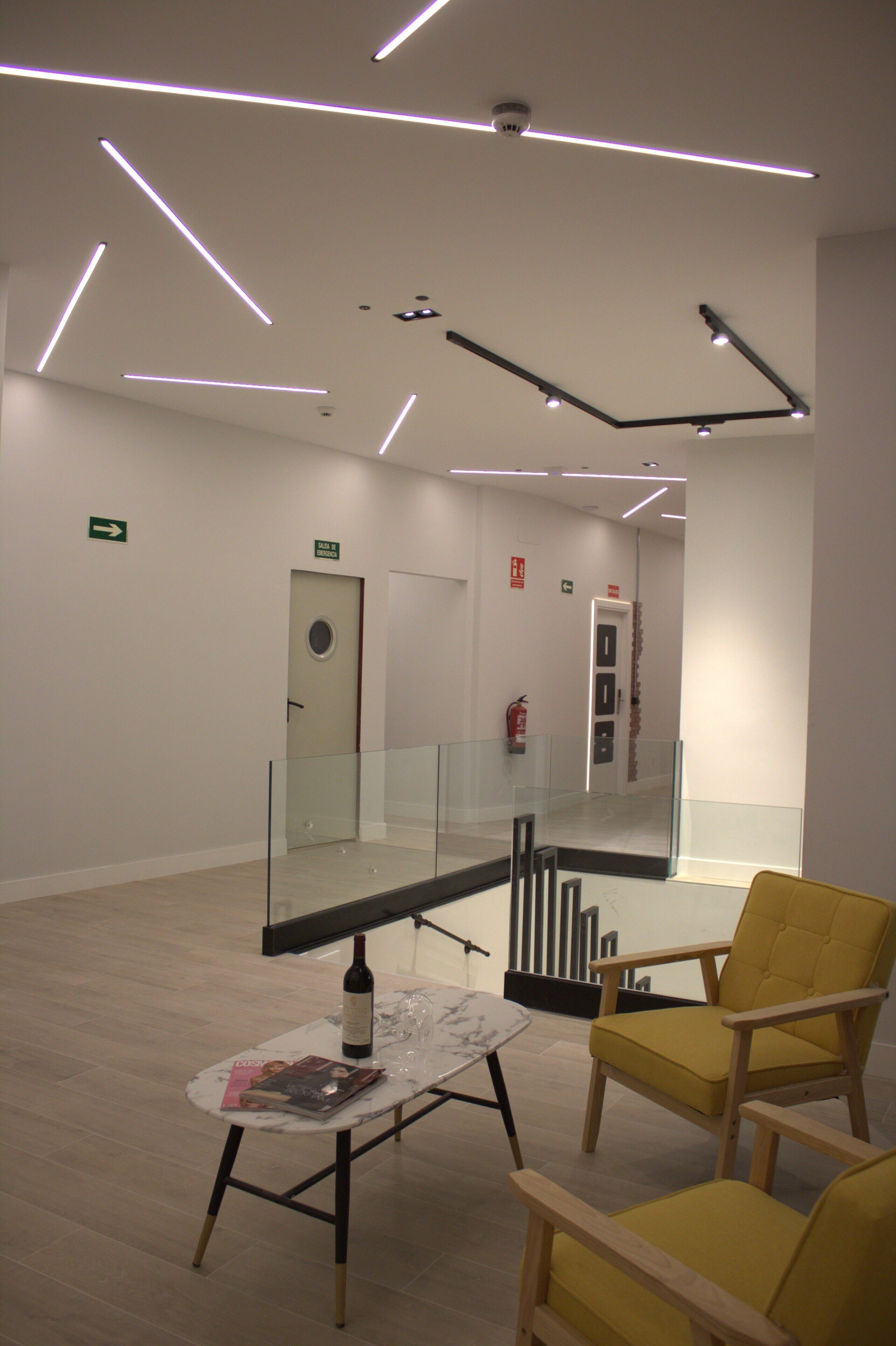 Een modern interieur met een glazen balustrade, een gele stoel en een tafel met een fles en tijdschrift.