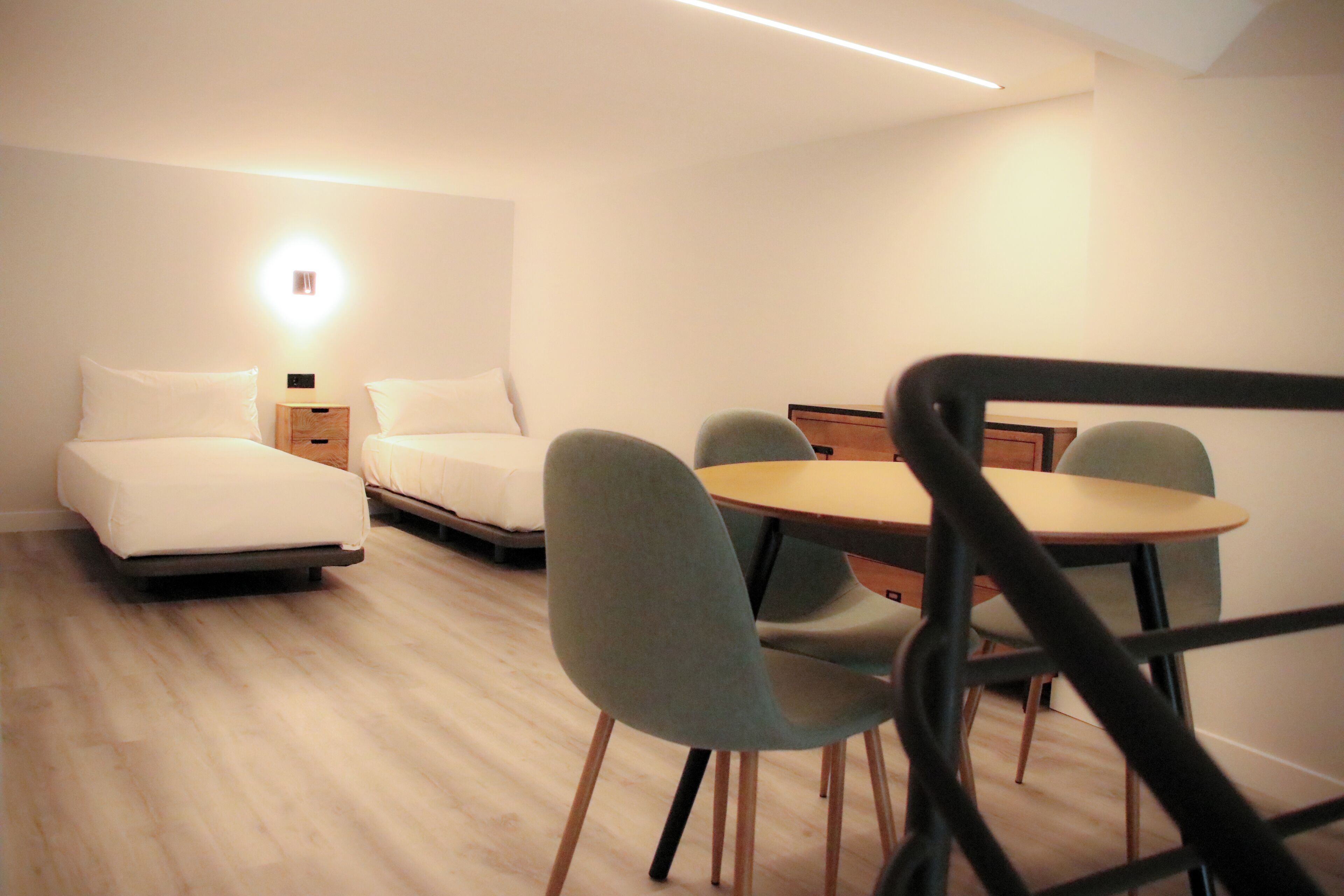Una habitación de hotel moderna con una cama, mesitas de noche, un escritorio y dos sillas.