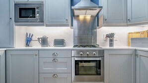 Cucina moderna con mobili grigi, forno a microonde integrato, cappa aspirante e forno in acciaio inossidabile.