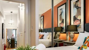 Una camera d'hotel con un letto, due comodini con lampade, uno specchio e una pianta in vaso.