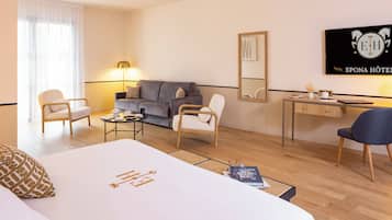 A hotel room with a bed, two armchairs, a sofa, a desk, and a lamp.