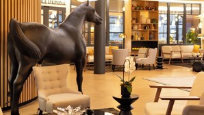 Un moderno vestíbulo con una gran escultura de caballo, zonas de estar y un interior bien iluminado.